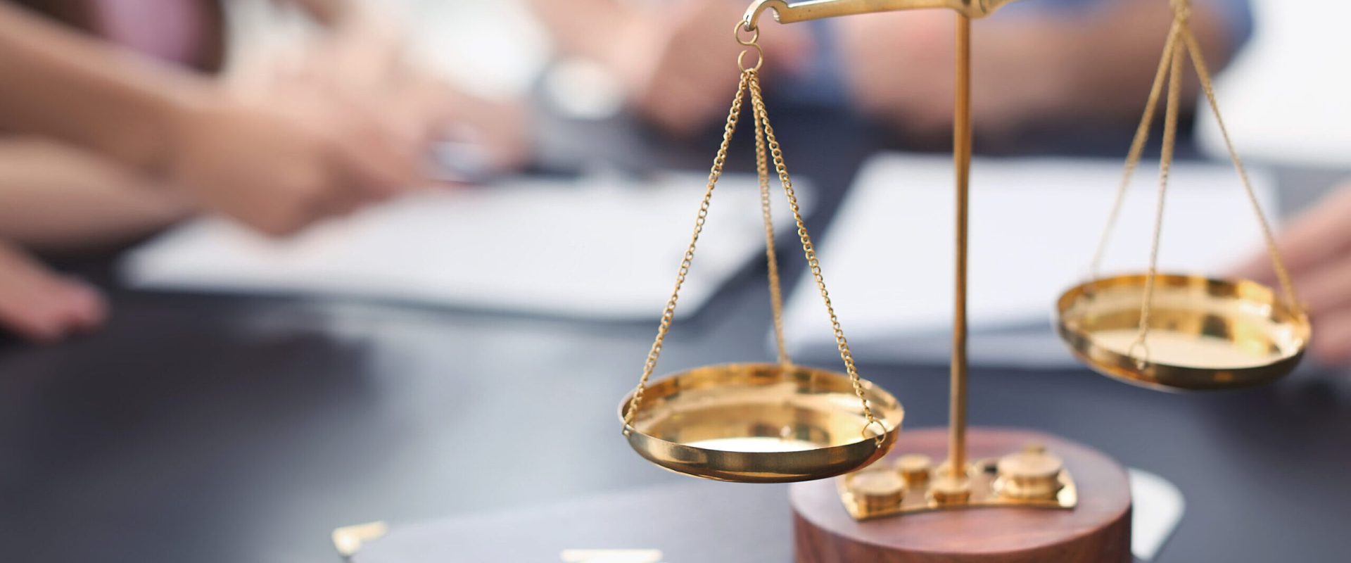Scales of justice with juridical book on table in lawyer's office